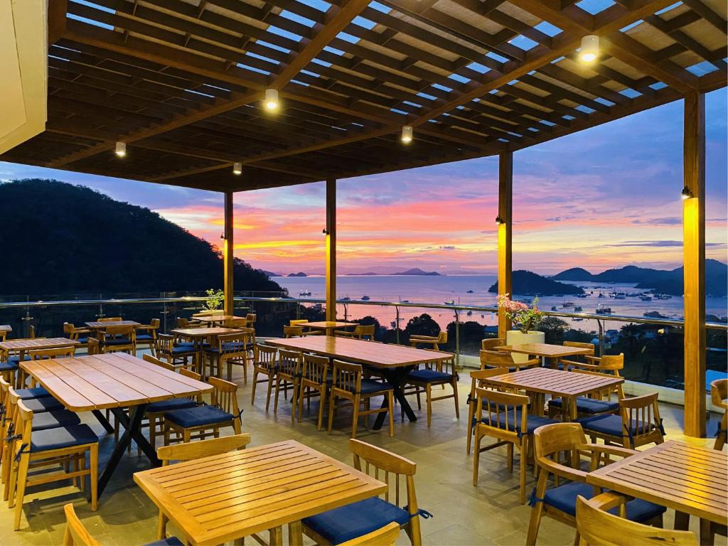 un restaurant avec des tables et des chaises et un coucher de soleil dans l'établissement Zasgo Hotel, à Labuan Bajo