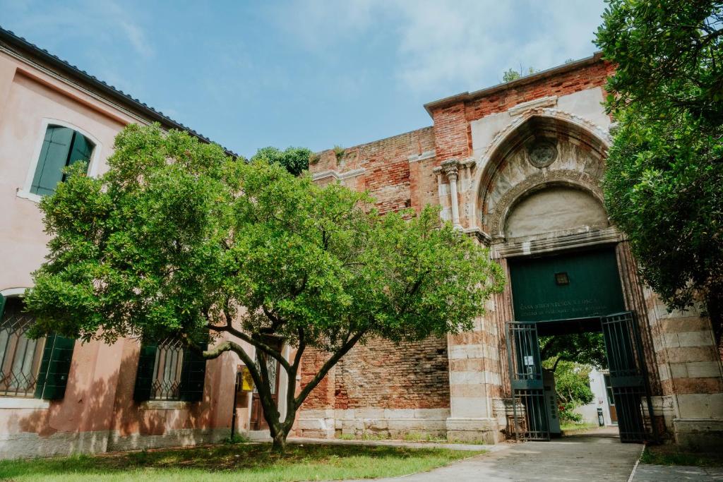 um velho edifício de tijolos com uma árvore em frente em Ostello S. Fosca - CPU Venice Hostels em Veneza