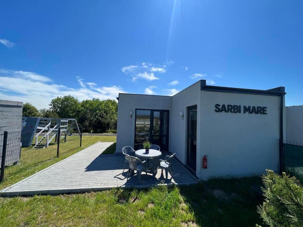 un petit bâtiment blanc avec une table sur une terrasse dans l'établissement Sarbi Mare, à Sarbinowo