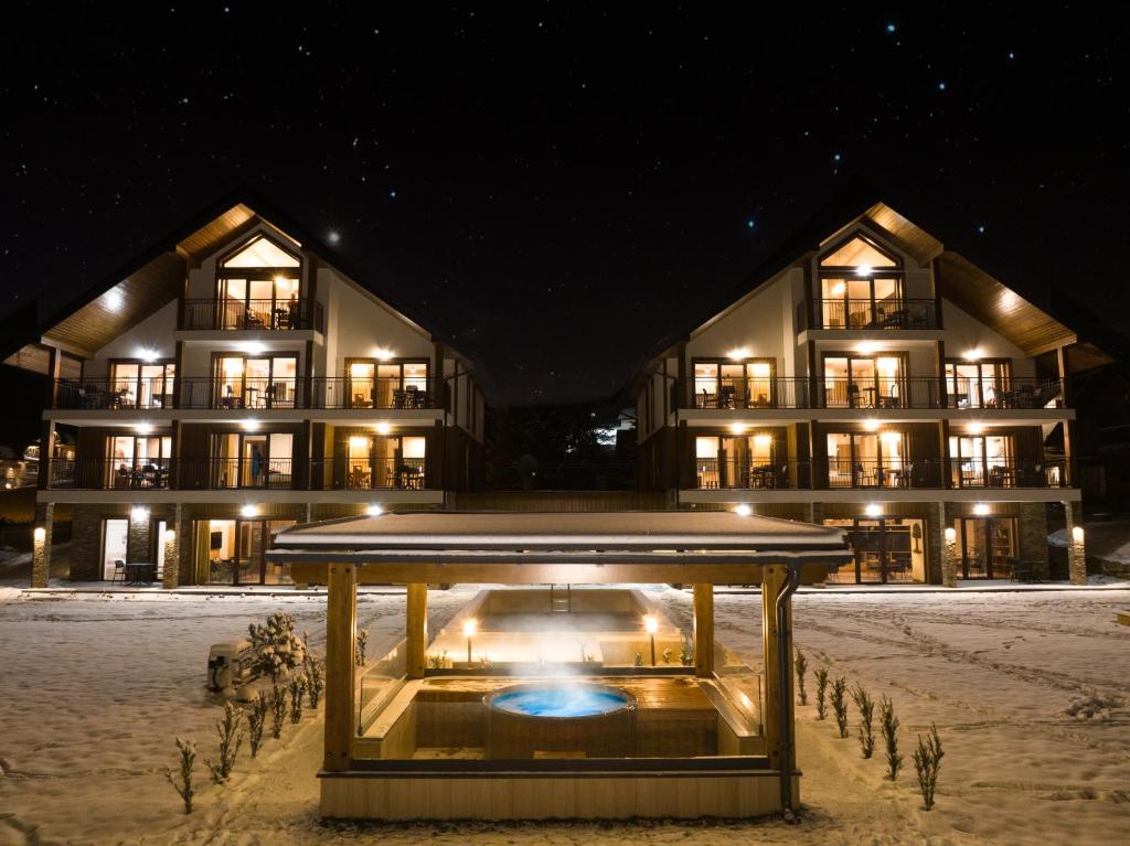 un grande edificio nella neve di notte di Apartamenty Mariza Szczawnica Jaworki - sauna, balia, opcja śniadań bufetowcyh, piękne i nowe apartamenty 1km od stoku a Szczawnica