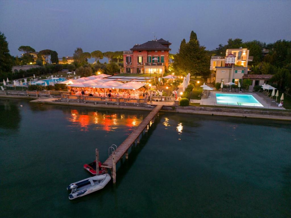 uma doca com um restaurante e um barco na água em Villa Pioppi Hotel em Sirmione