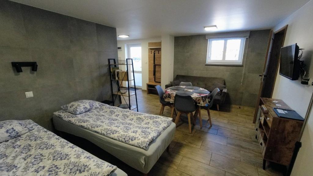 ein Zimmer mit 2 Betten und einem Tisch sowie ein Zimmer mit einem Esszimmer in der Unterkunft Przystanek Tykocin - apartamenty gościnne in Tykocin