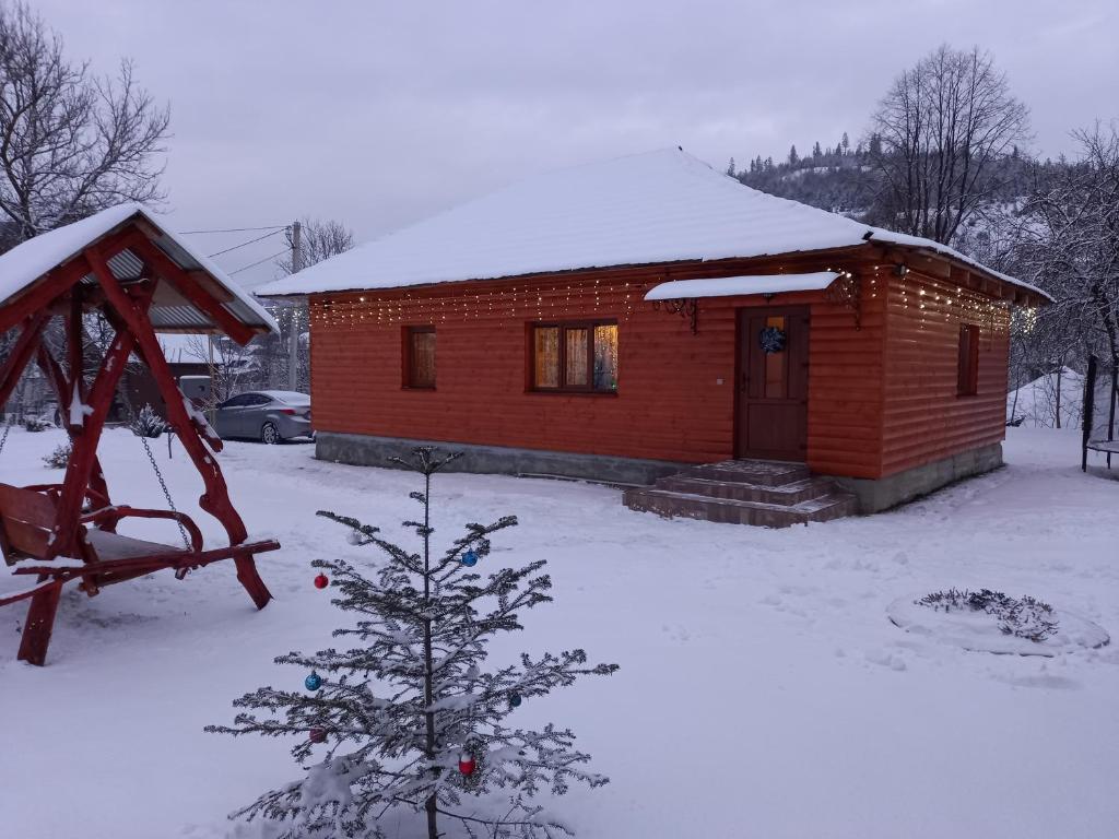 Cabaña de madera pequeña con techo cubierto de nieve en Котедж "Затишний відпочинок", en Huklyvyy