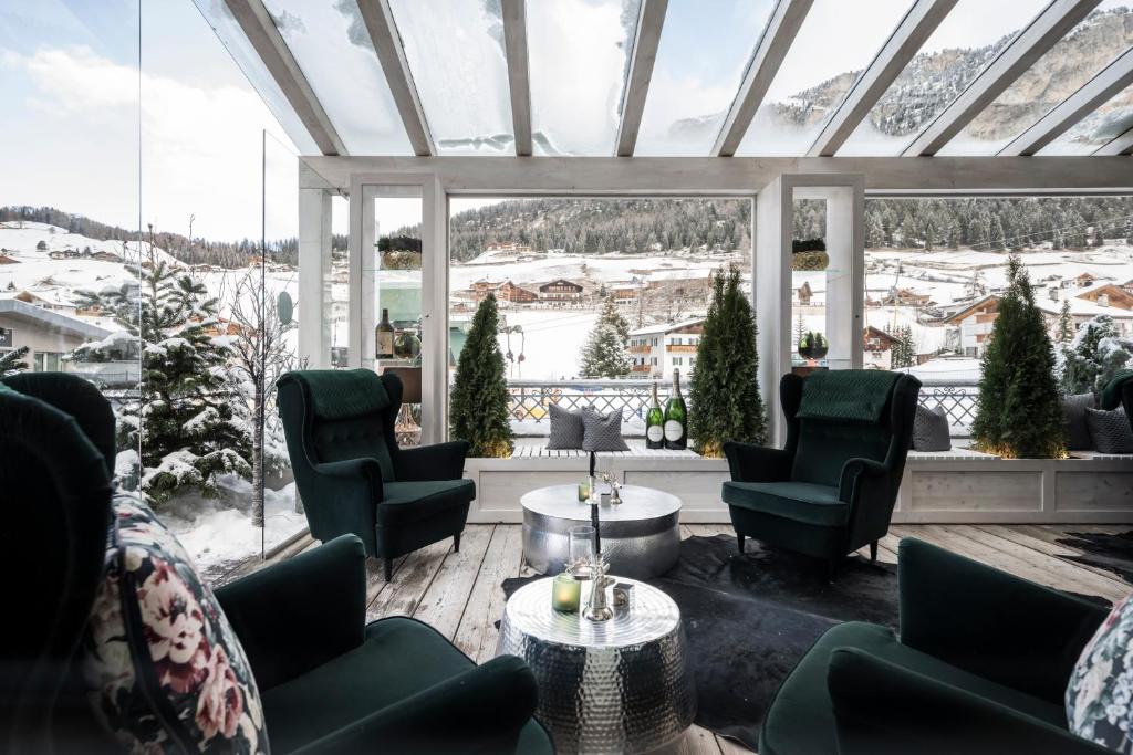 a conservatory with chairs and tables and a large window at Hotel Acadia - Adults Mountain Home in Selva di Val Gardena