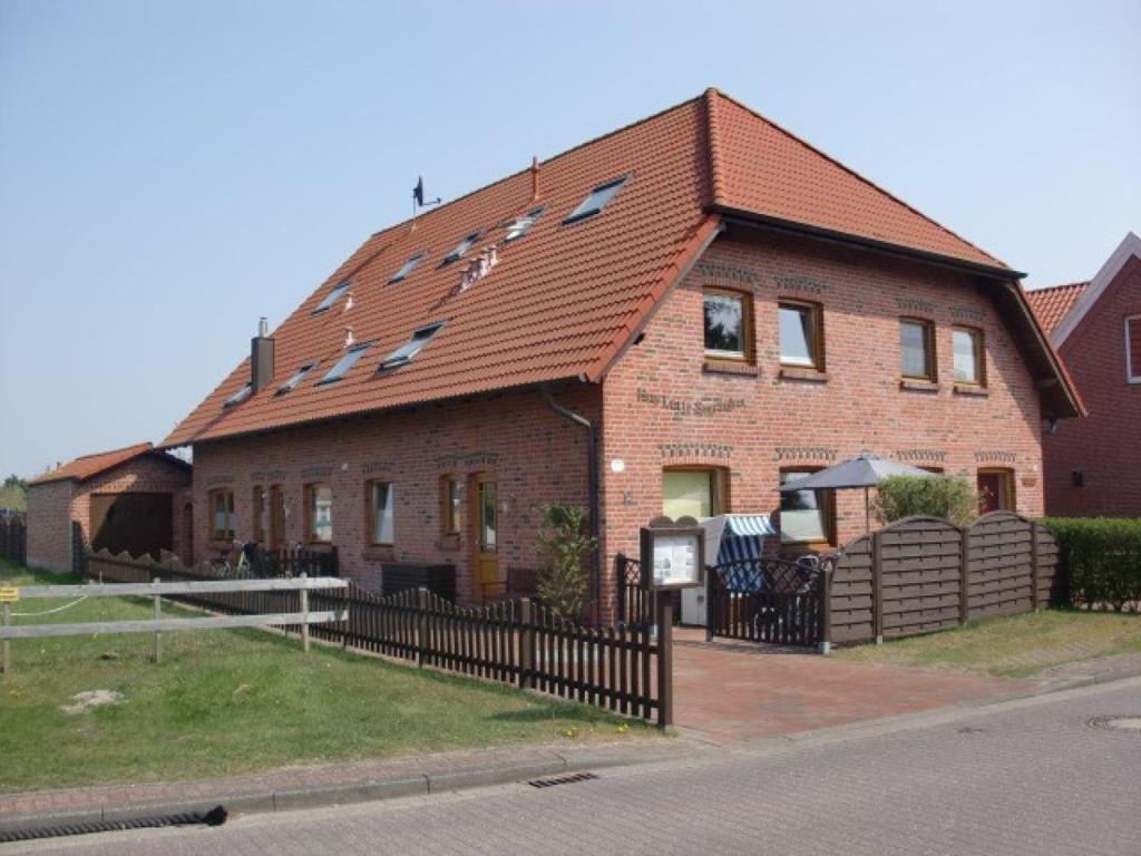 een groot bakstenen huis met een bruin dak bij Krabbe in Borkum