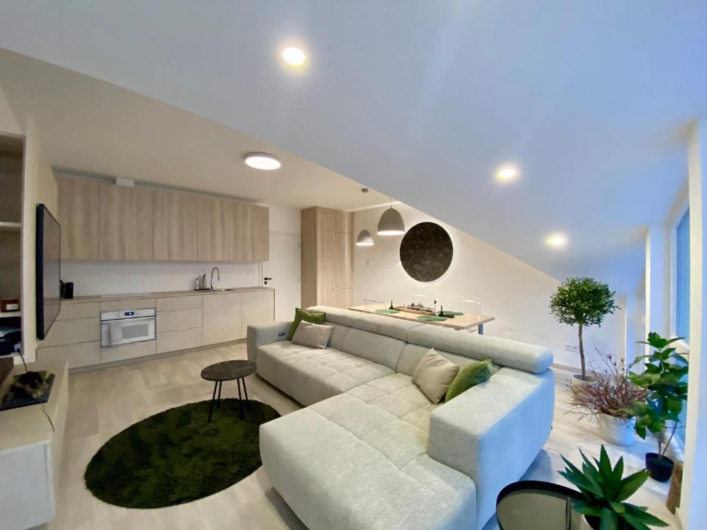 a living room with a white couch and a kitchen at Loft Vrchlabí in Vrchlabí