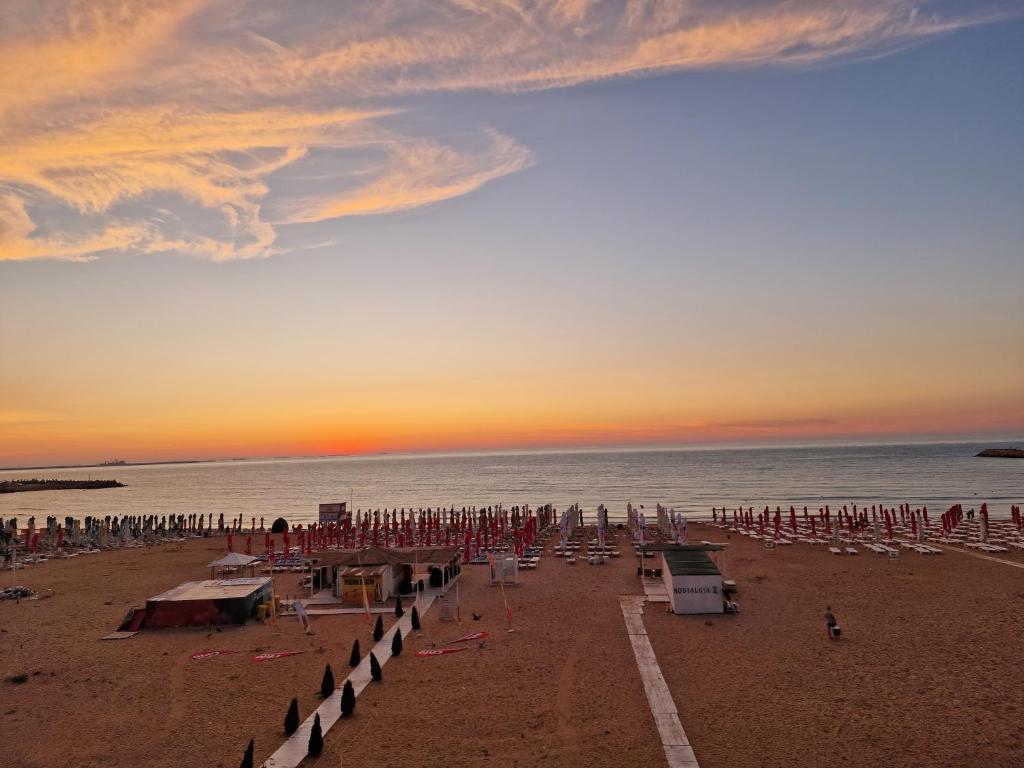 a beach with chairs and umbrellas at sunset at Hotel H pe plaja Belona in Eforie Nord