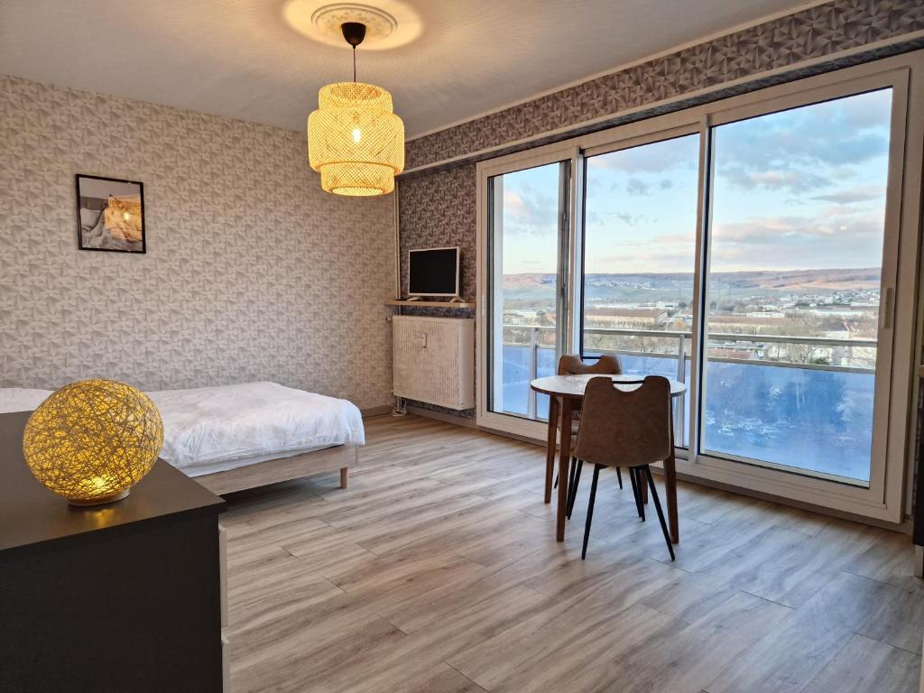 1 dormitorio con cama, escritorio y mesa con sillas en Studio avenue de Champagne, en Épernay