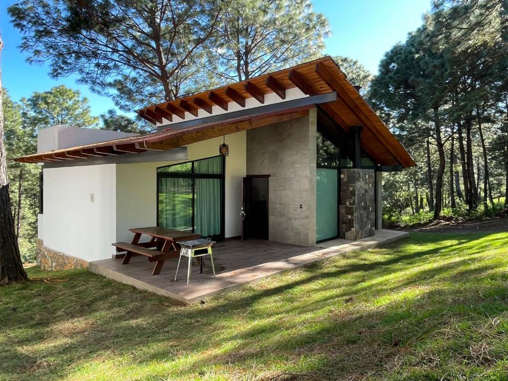 una pequeña casa con una mesa de picnic en un campo en Las Nubes, en Mazamitla