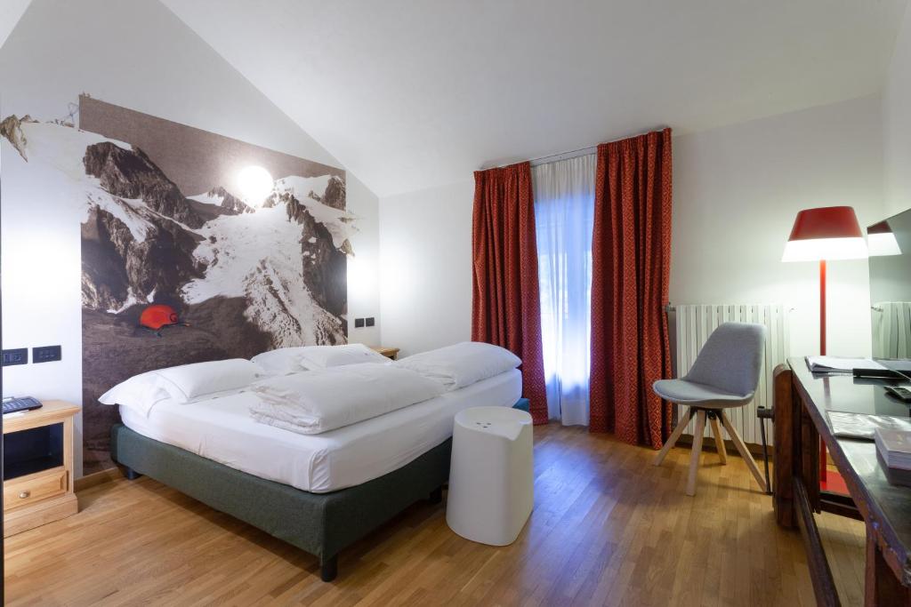 ein Hotelzimmer mit einem Bett und einem Schreibtisch in der Unterkunft Hotel Berthod in Courmayeur