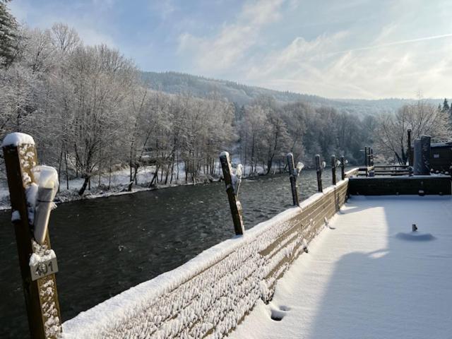 ogrodzenie ze śniegiem na nim obok rzeki w obiekcie Hotel Val De La Cascade w mieście Stavelot