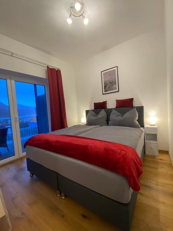 um quarto com uma cama grande e um cobertor vermelho em CityLake G23 Apartments mit kostenlosem Parkgaragen-Stellplatz !! em Gmunden