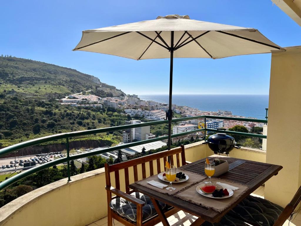 einen Tisch mit Sonnenschirm auf dem Balkon in der Unterkunft Casa do Mar - Sea view - Wifi - Barbecue in Sesimbra