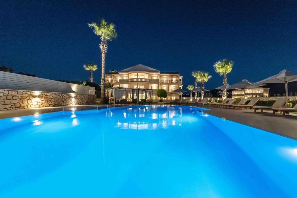 uma grande piscina em frente a uma casa à noite em San Giovanni Beach Resort and Suites em Lefkada Town