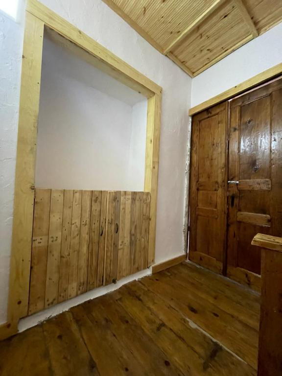 um quarto vazio com uma porta grande e pisos em madeira em Ardjon House em Berati