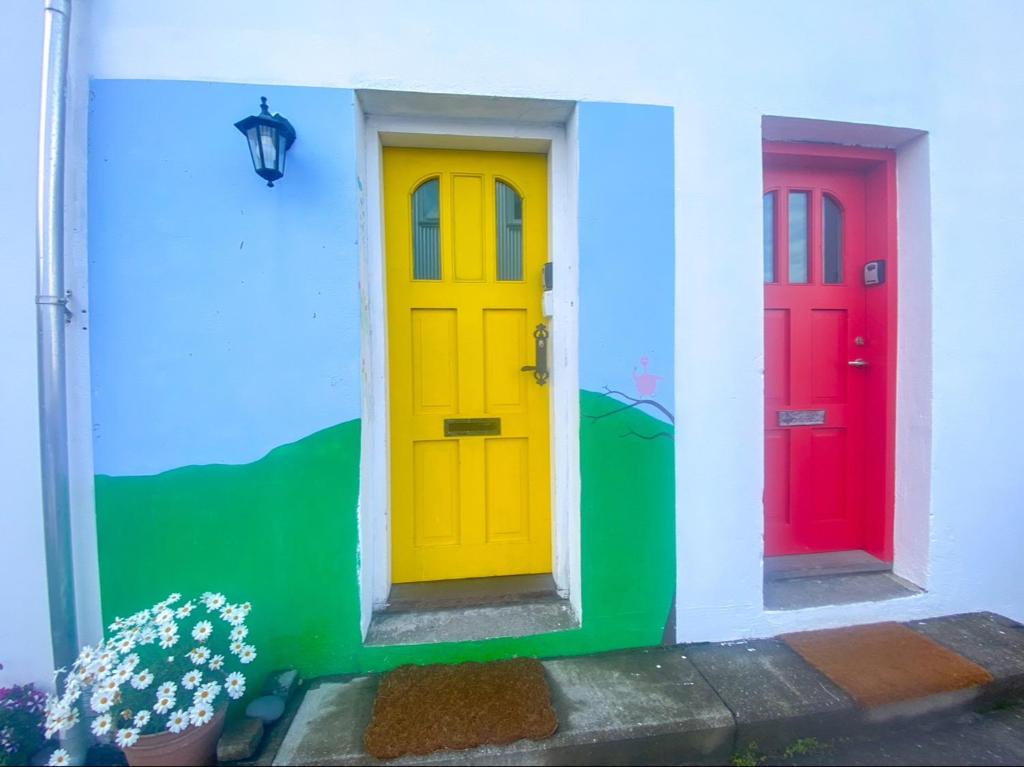 Trois portes colorées sur une maison fleurie dans l'établissement Enjoy Reykjavík Yellow Door Apartment, à Reykjavik