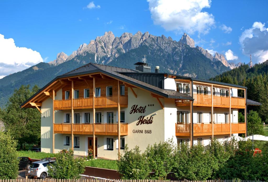 un grande edificio con montagne sullo sfondo di B&B Hotel Heidi a Dobbiaco