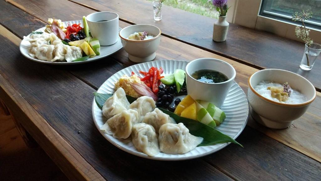 een houten tafel met borden en schalen van voedsel bij Tanehachi Farm Guesthouse - Vacation STAY 29709v in Aomori