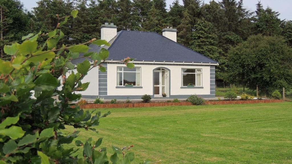 ein weißes Haus mit einem Garten mit grünem Rasen in der Unterkunft Green Acres Self Catering in Claremorris