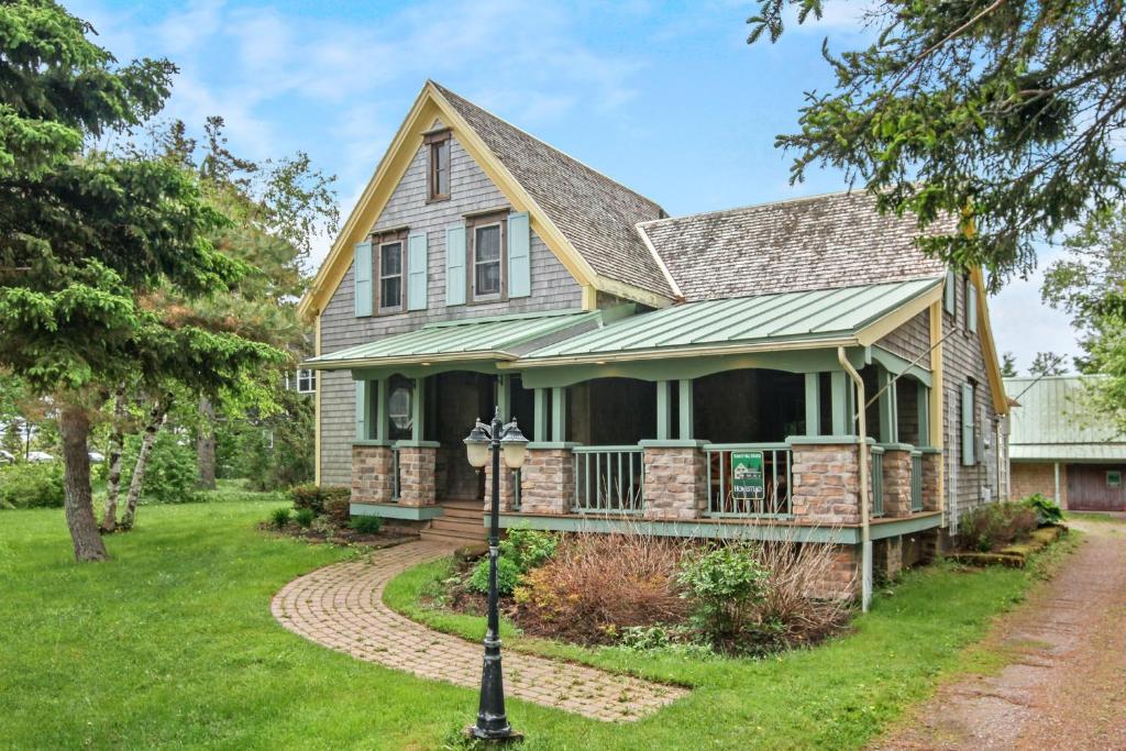 una casa con techo verde y porche en Avonlea Forest Hill Cottages, en New Glasgow