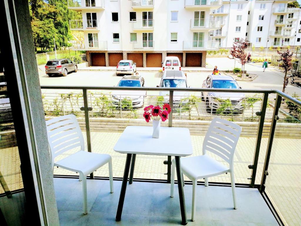 a table and chairs on a balcony with a vase of flowers at Sea Suite, 150 meters to beach, Baltic Best in Dziwnówek