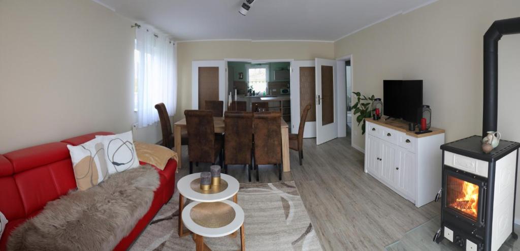 sala de estar con sofá rojo y chimenea en Apartment Am Mittelpunkt Deutschlands, en Niederdorla