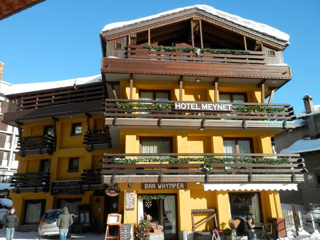 um edifício amarelo com uma placa de hotel em Hotel Meynet em Breuil-Cervinia