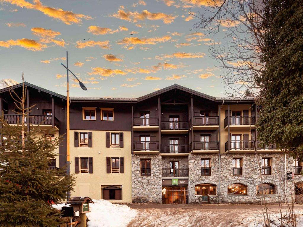 een appartementencomplex met sneeuw ervoor bij ibis Styles Les Houches Chamonix in Les Houches