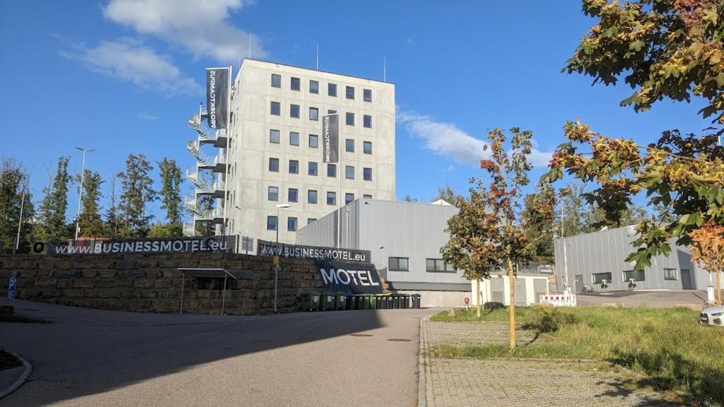 a large white building with a sign in front of it at Business-Motel, free XL-Parking, WiFi, massage-chairs, sauna, shared kitchen, breakfast 2go, free soda, coffee in Heimsheim