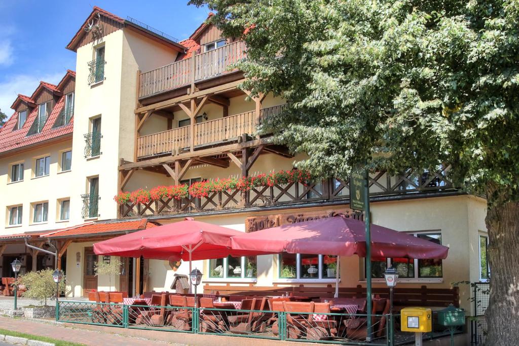 een restaurant met tafels en parasols voor een gebouw bij Hotel am Liepnitzsee in Wandlitz