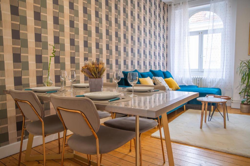 une salle à manger avec une table et un canapé bleu dans l'établissement Plumeria - Grand Appartement 75m2 - Au calme - Proche Gare, Nouvelle Ville - Parking Public Gratuit - 2 Chambres - 4 Lits séparés, à Metz