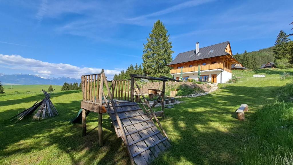 een speeltuin in een veld naast een huis bij Drevenica pod Demänovskou horou in Demanovska Dolina