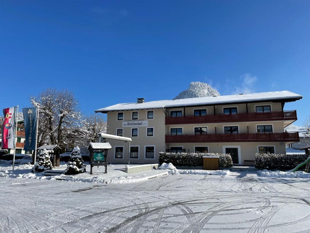 un grand bâtiment avec de la neige devant lui dans l'établissement Hotel-Restaurant Stefanihof, à Fuschl am See