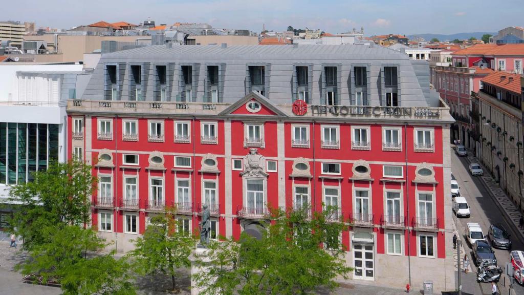 a red building with a clock on top of it at NH Collection Porto Batalha in Porto