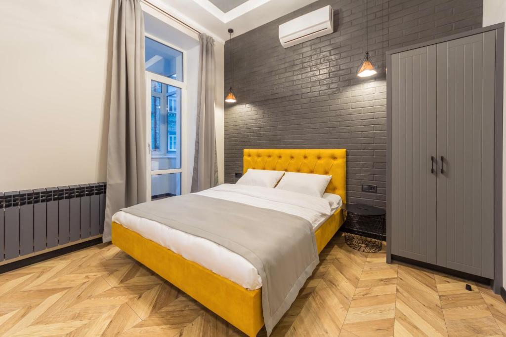 Un dormitorio con una cama amarilla y una pared de ladrillo en Self Check-in Apartments Maidan Area, en Kiev