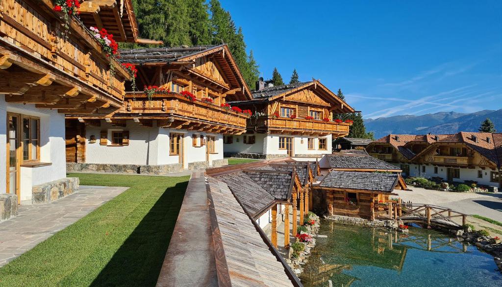 un gruppo di edifici in legno con acqua di fronte di Chalets Almdorf Haidenberg a Brunico