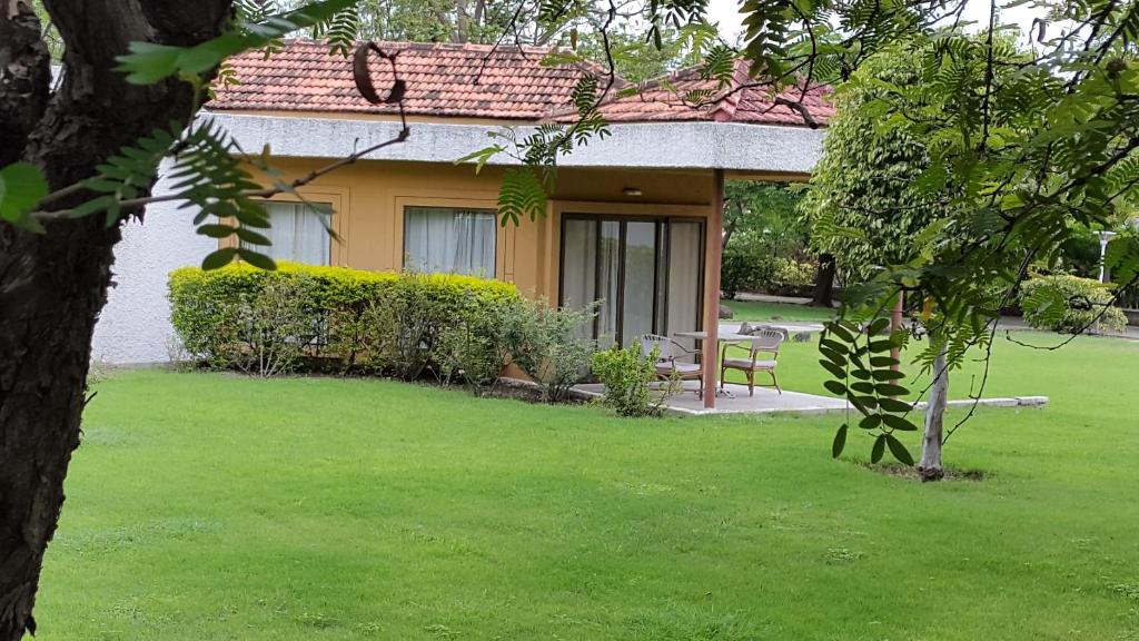 ein Haus mit grünem Rasen davor in der Unterkunft The Meadows Resort and Spa in Aurangabad