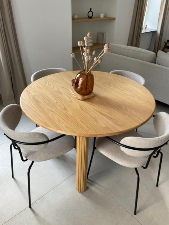 a wooden table with chairs and a vase with flowers at L'Apothèque - Résidence Le Cercle in Marche-en-Famenne