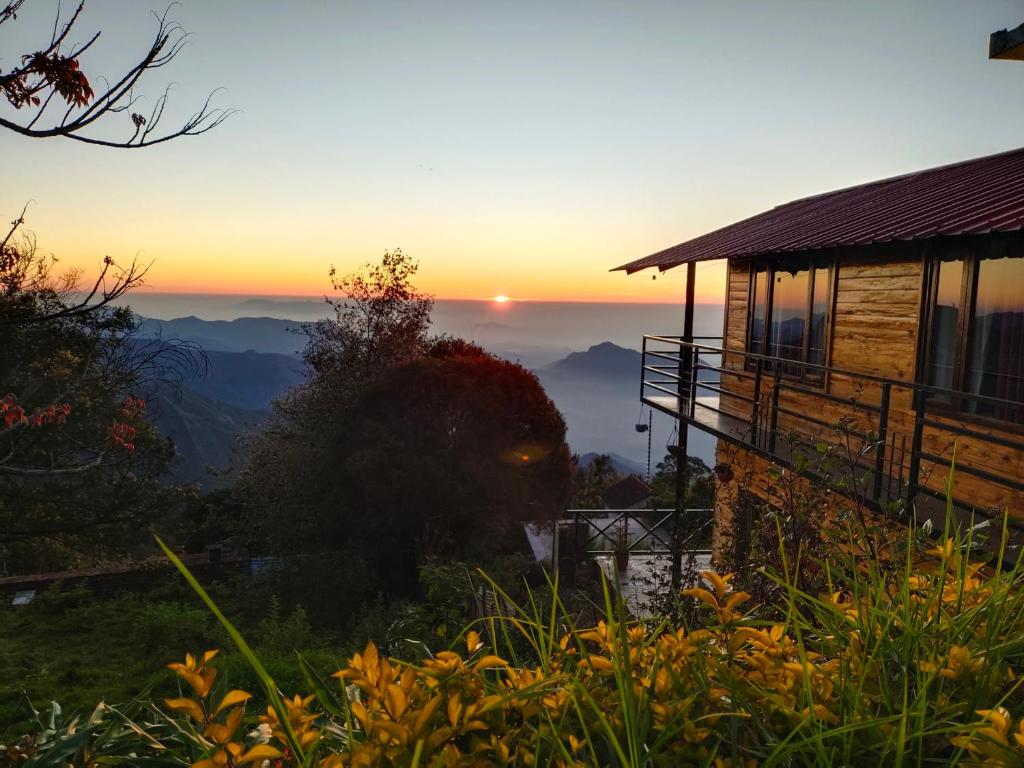 een huis met de zonsondergang op de achtergrond bij MISBHA HomeStay in Kodaikānāl