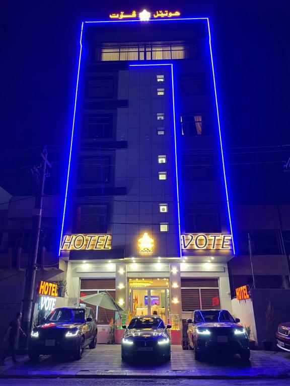 hotel z samochodami zaparkowanymi przed nim w nocy w obiekcie Vote Hotel w mieście Irbil