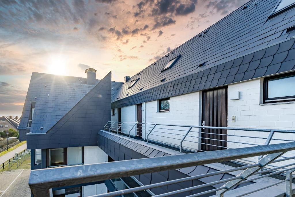 a building with a balcony with the sun in the background at Möwennest App 18 in Wenningstedt