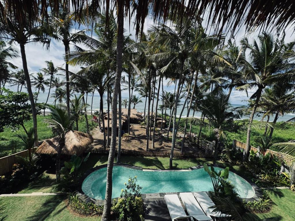 una piscina en un complejo con palmeras en Uma Pantai Seseh, en Canggu