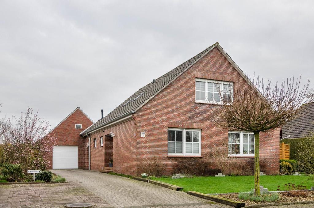 een rood bakstenen huis met een witte garage bij Ferienwohnung Utkiek in Ihlow