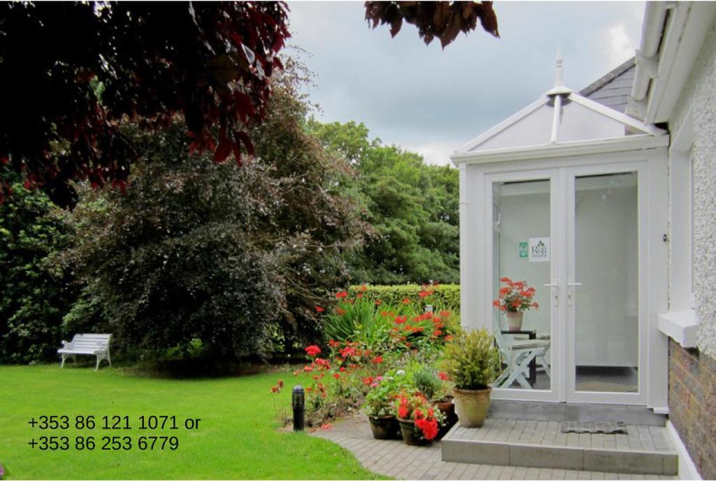 un vivero blanco en un jardín con flores y plantas en Conways B&B, en Claremorris