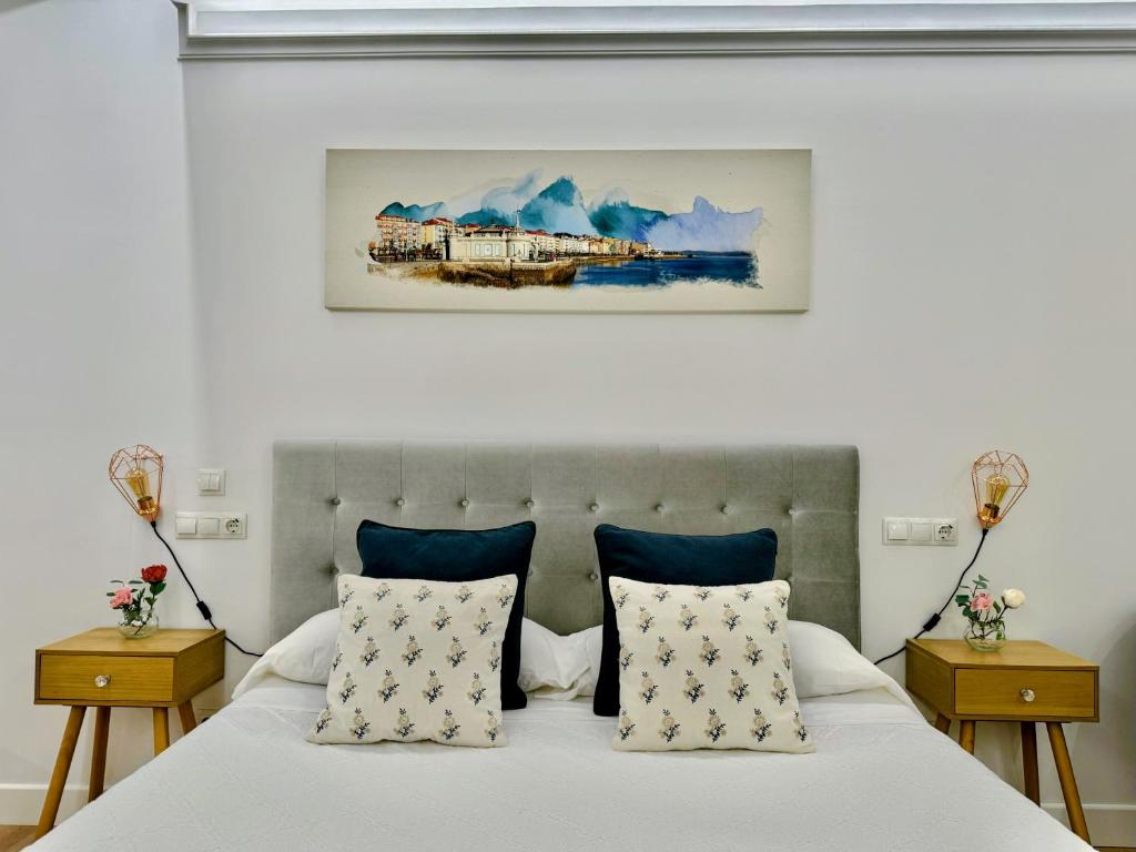 a bedroom with a bed with blue pillows and a painting at LOFT CENTRE SANTANDER in Santander