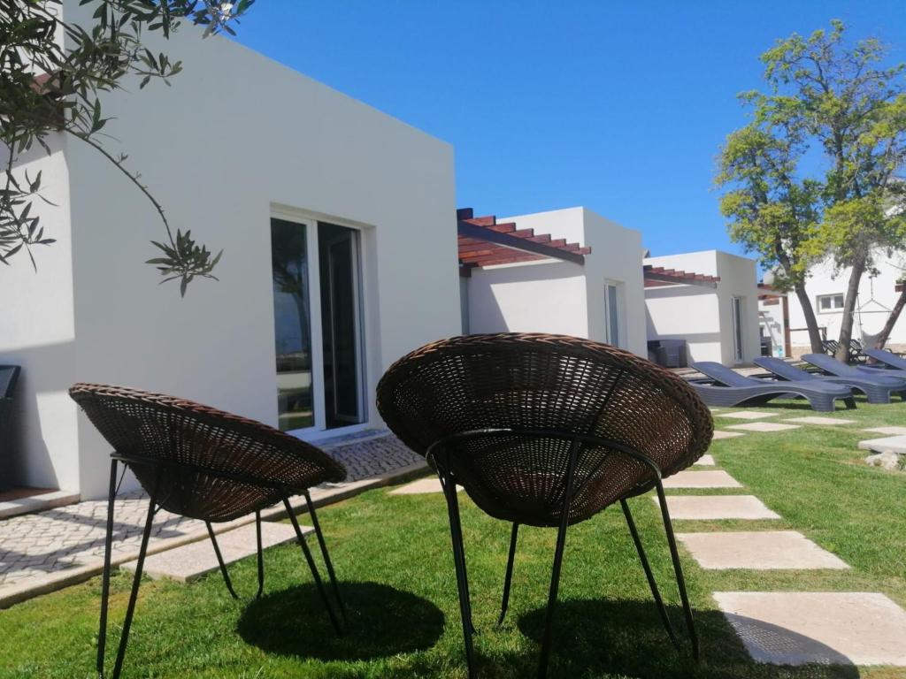 dos sillas sentadas en el césped frente a una casa en Furnaka Eco Village, en Lourinhã