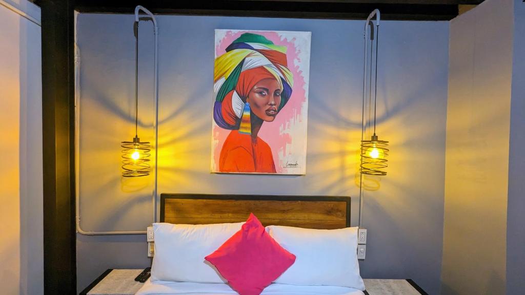 een slaapkamer met een bed met een schilderij aan de muur bij Maloka Boutique Hostel in Cartagena