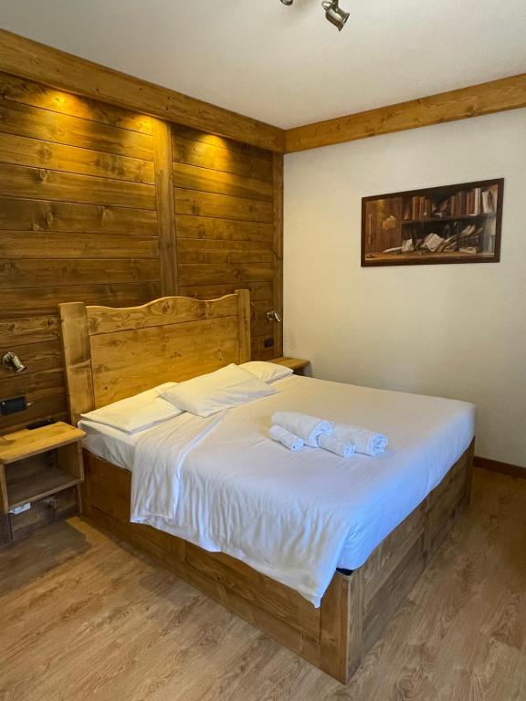 sypialnia z dużym łóżkiem i drewnianymi ścianami w obiekcie Hotel Oasi w mieście San Vito di Cadore