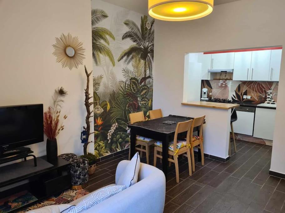 sala de estar con sofá, mesa y cocina en L’Oasis Fleuri, en Bourg-de-Péage