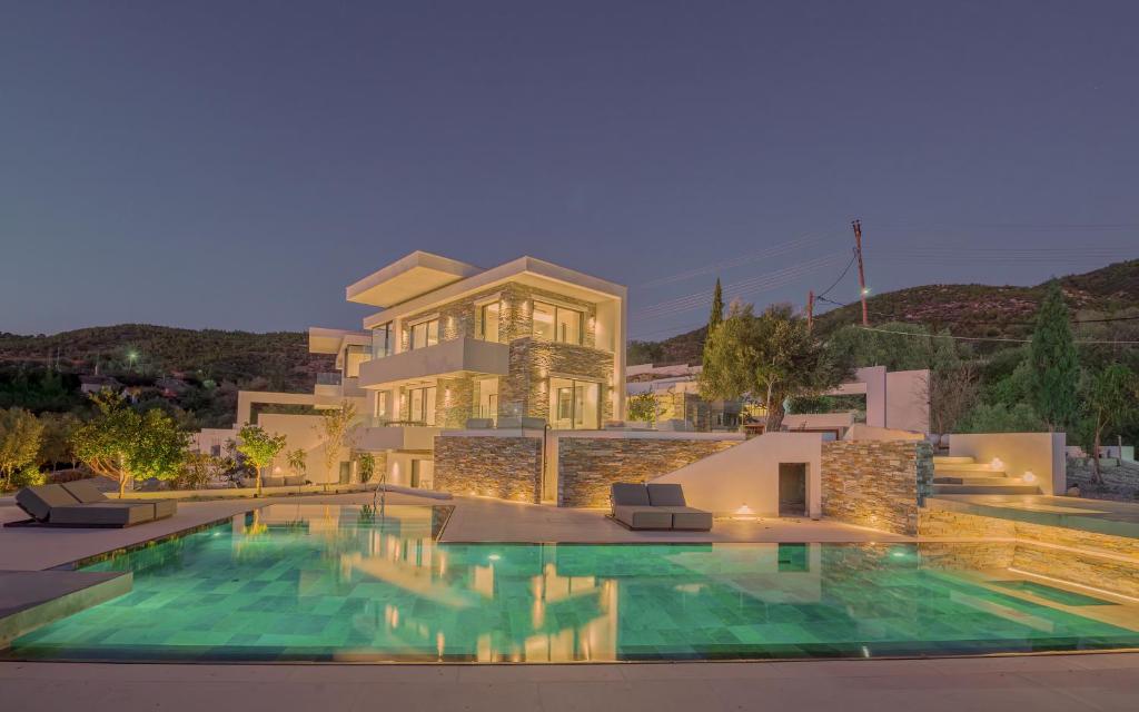 a house with a swimming pool in front of a building at Elia Cove Luxury Villa with private Grand Pool in Korinthos